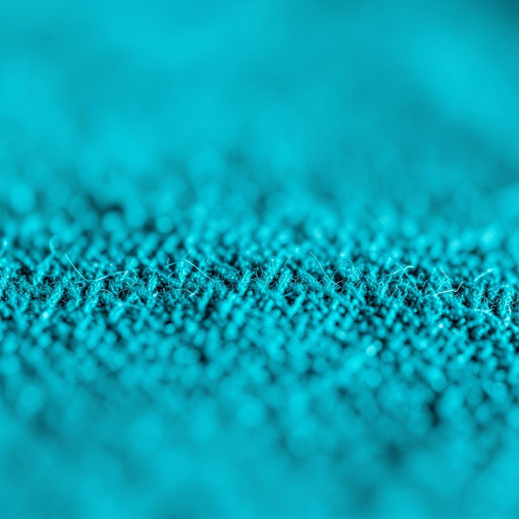 Extreme close-up photograph of smooth pale river stones in soft teal and grey tones, arranged in a calm meditative pattern with a serene, soothing mood.